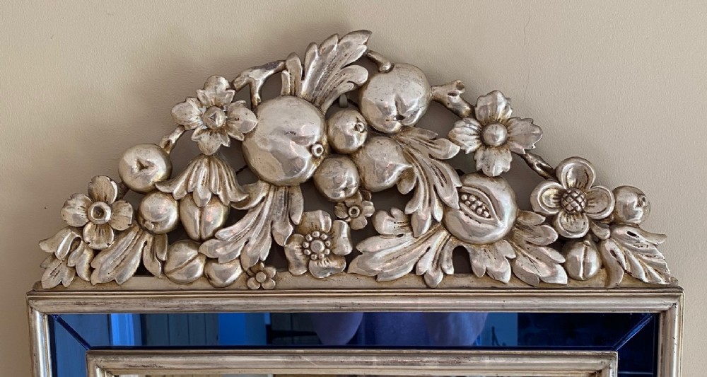 A vertical rectangular Venetian wall mirror featuring a carved silvered fruit pediment, silver gilt framing, and cobalt blue glass border panels. View III