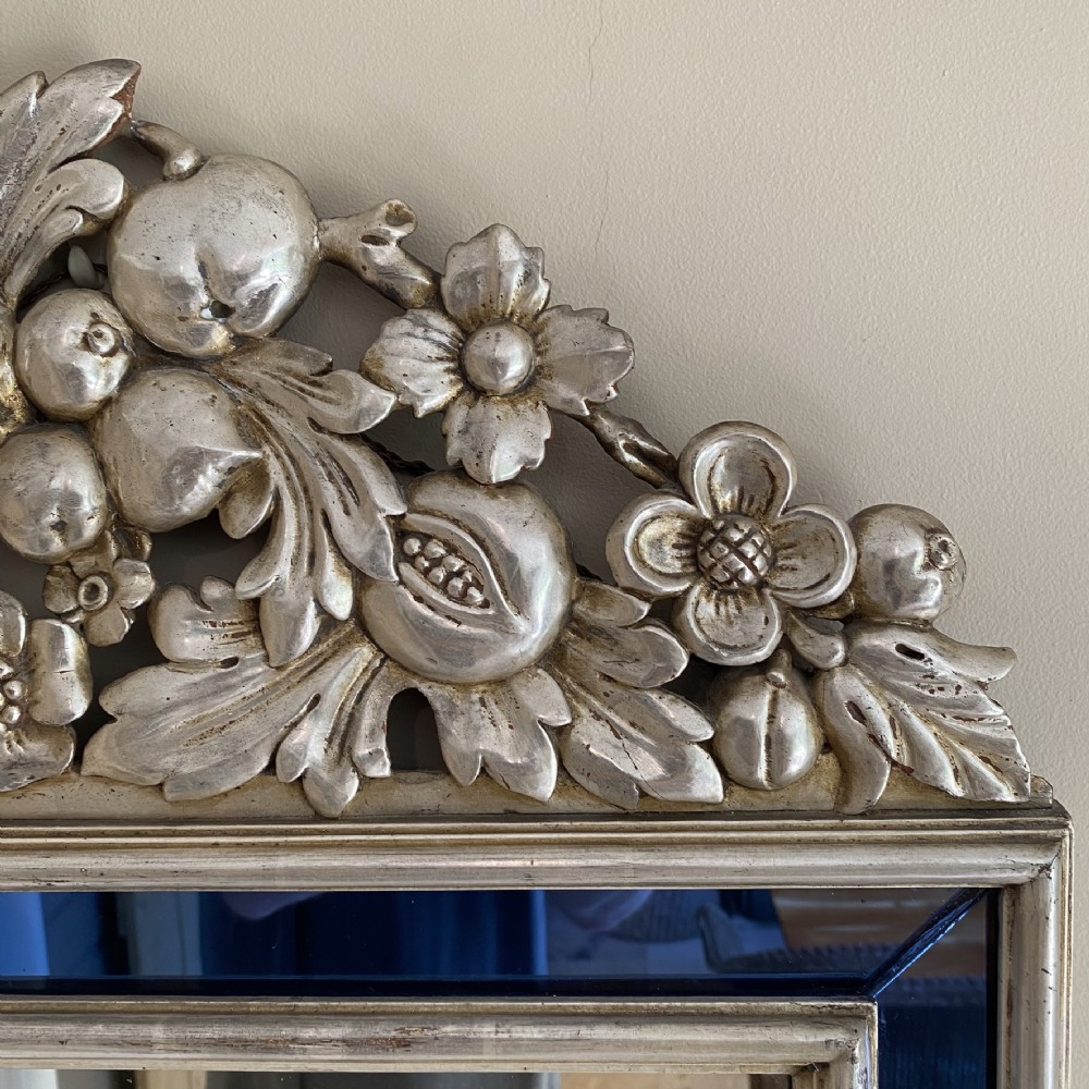 A vertical rectangular Venetian wall mirror featuring a carved silvered fruit pediment, silver gilt framing, and cobalt blue glass border panels. View IV