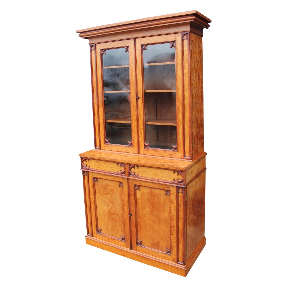A 19th century Gothic Revival two-part satinwood bookcase featuring glazed upper doors with Gothic tracery and a matching lower cupboard section. View II