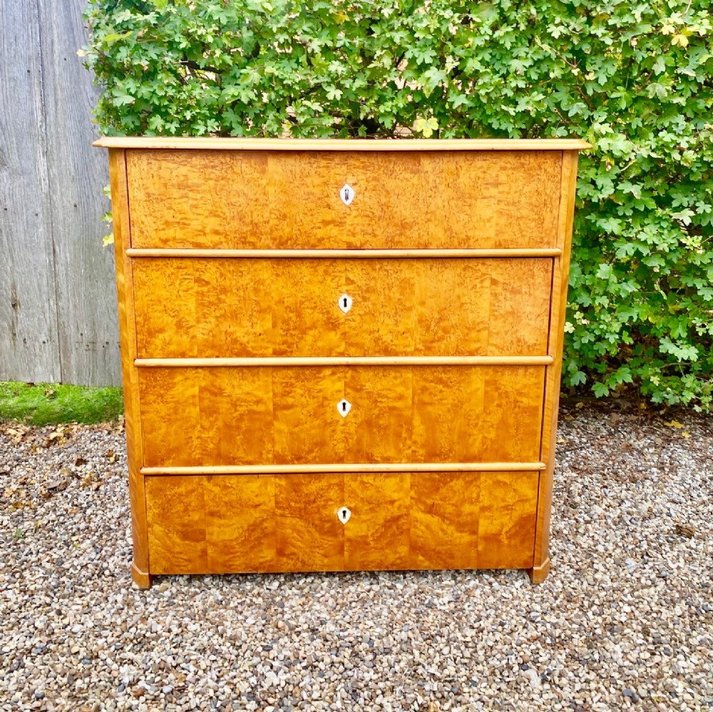 A mid-19th-century Swedish satin birch chest featuring four straight drawers with central keyhole escutcheons.