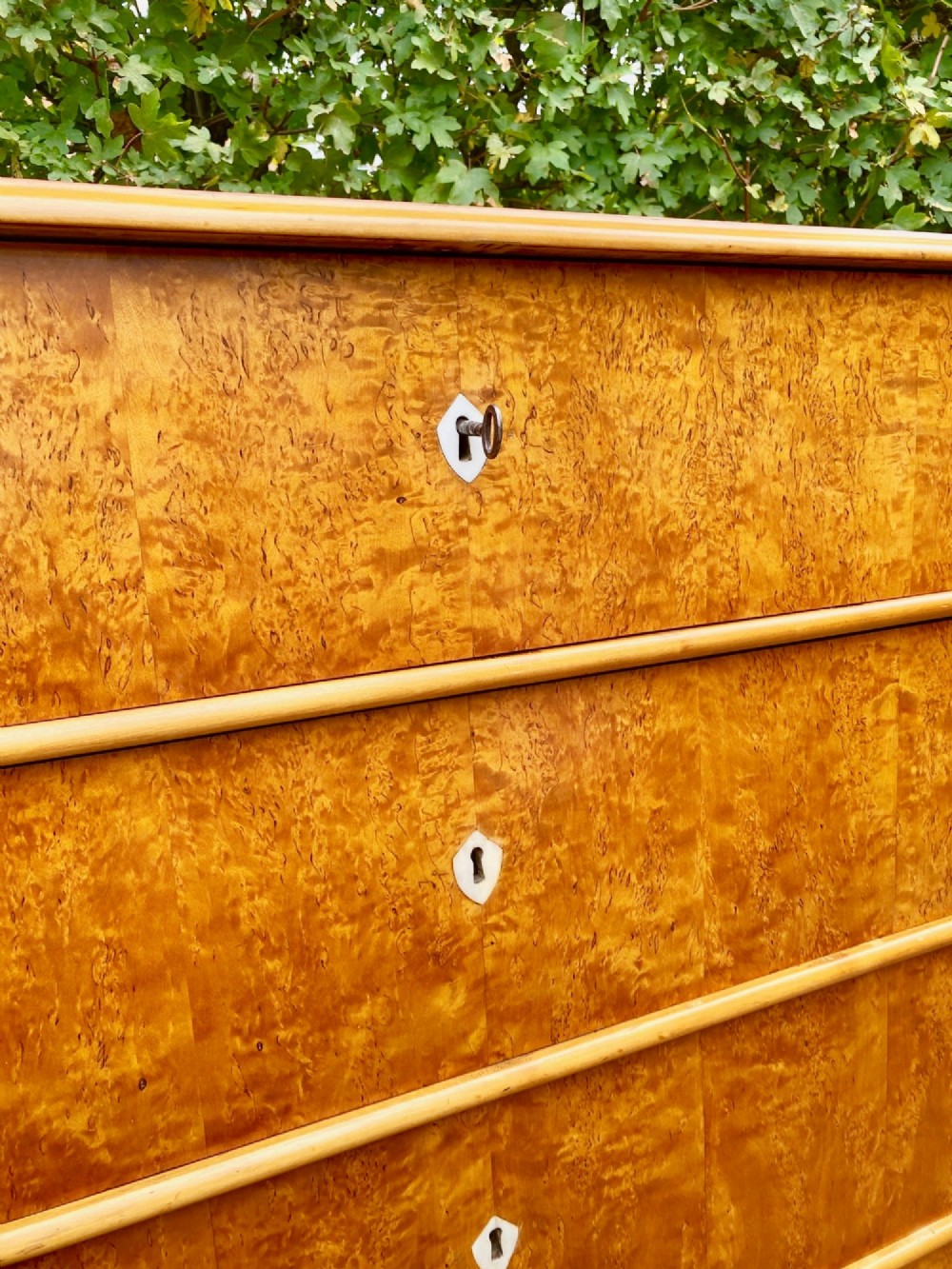 A mid-19th-century Swedish satin birch chest featuring four straight drawers with central keyhole escutcheons. View IV