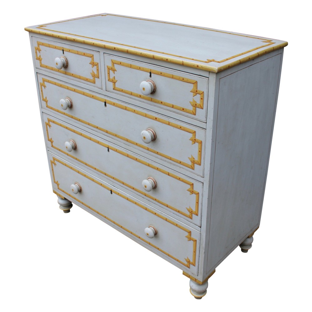 A nineteenth-century off-white painted chest of drawers featuring decorative yellow faux bamboo borders, wooden knobs, and turned feet. View II