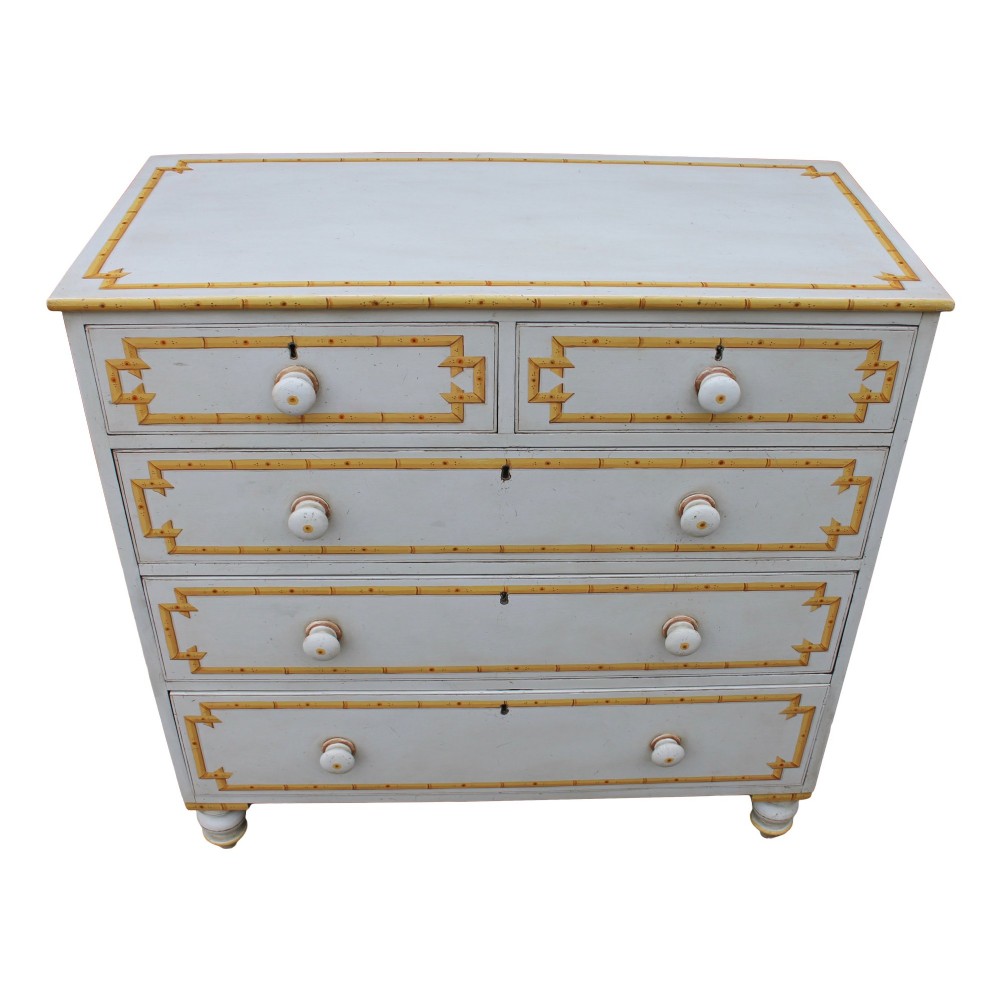 A nineteenth-century off-white painted chest of drawers featuring decorative yellow faux bamboo borders, wooden knobs, and turned feet. View IV