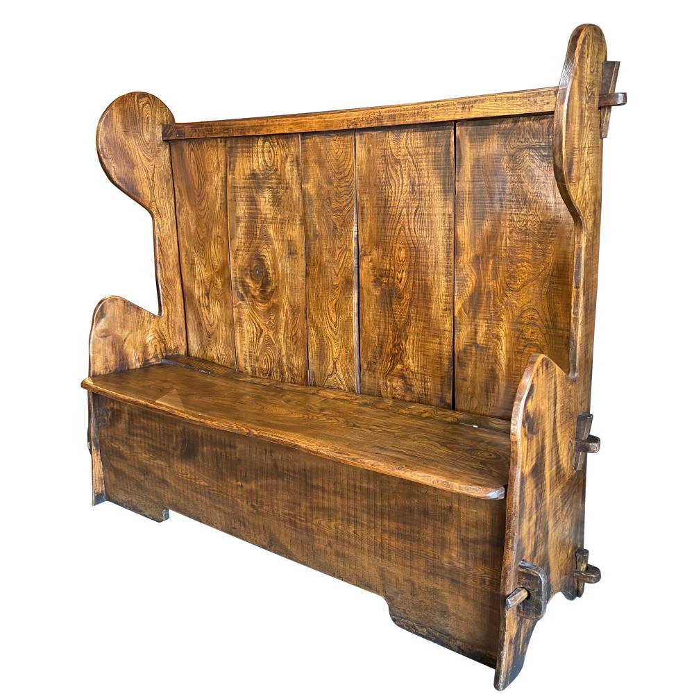 A high-backed 19th-century solid elm box settle with shaped side wings, panelled backrest, and integrated storage seat. View III