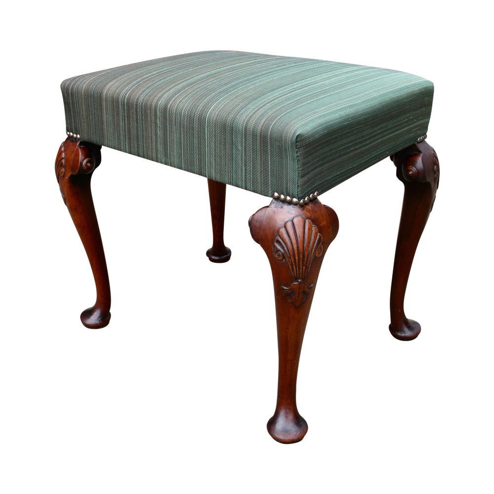 A rectangular upholstered stool featuring green striped fabric, brass tack trimming, and four carved solid walnut cabriole legs with shell motifs on the knees.