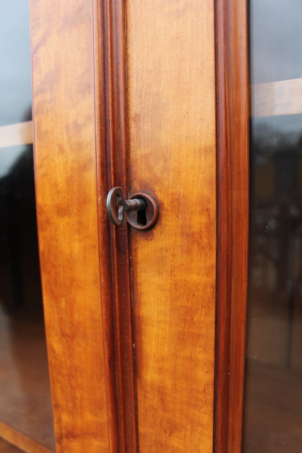 A 19th-century Gothic Revival two-part satinwood bookcase featuring a glazed upper cabinet with tracery trim above a solid door base. View IV