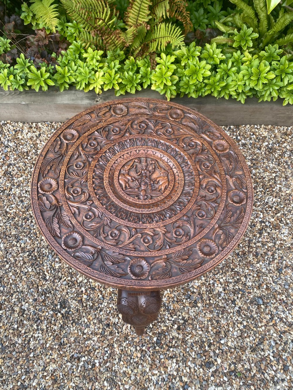 A circular carved rosewood side table supported by three legs shaped as detailed elephant heads with trunks extending to the floor. View III