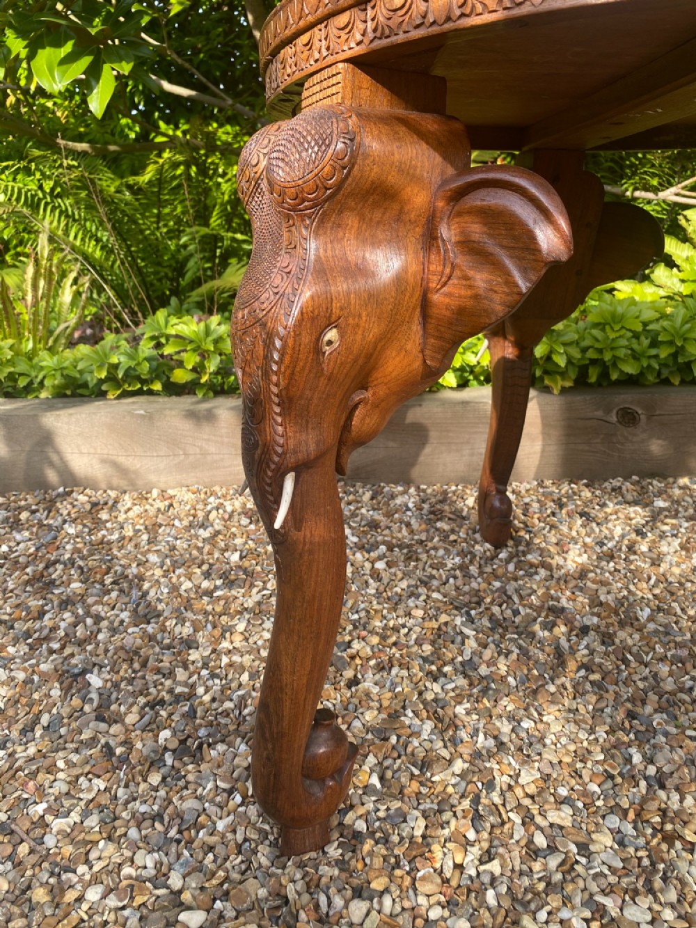 A circular carved rosewood side table supported by three legs shaped as detailed elephant heads with trunks extending to the floor. View V