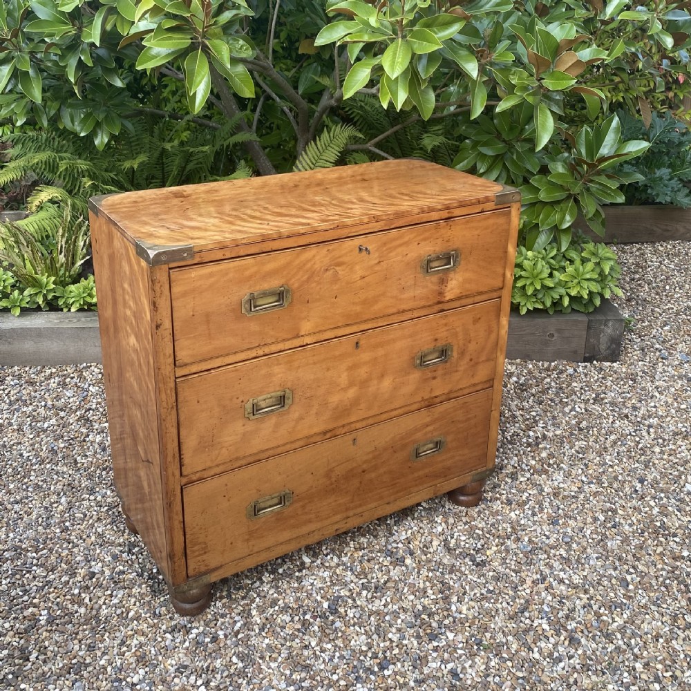 A mid-19th-century satin birch military campaign chest featuring three full-width drawers with flush recessed brass handles and corner brass protective brackets. View IV