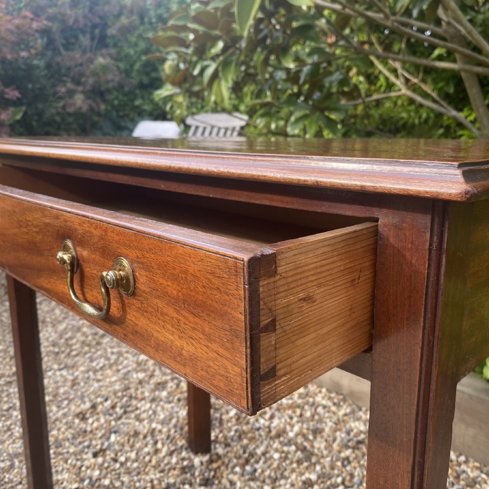 An 18th-century Georgian mahogany side table featuring a single drawer with two brass swan-neck handles and square legs. View VI