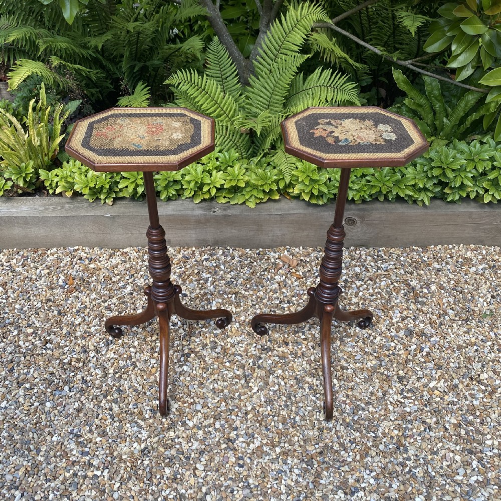 A pair of Georgian dark mahogany wine tables featuring octagonal tops with floral needlepoint inserts, slender ring-turned pedestals, and tripod downswept legs.