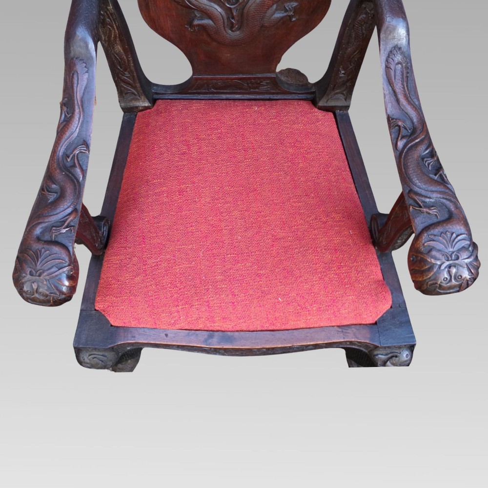 A pair of dark carved hardwood armchairs featuring high back splats with dragon relief motifs, dragon head terminal arms, and red upholstered seats. View IV