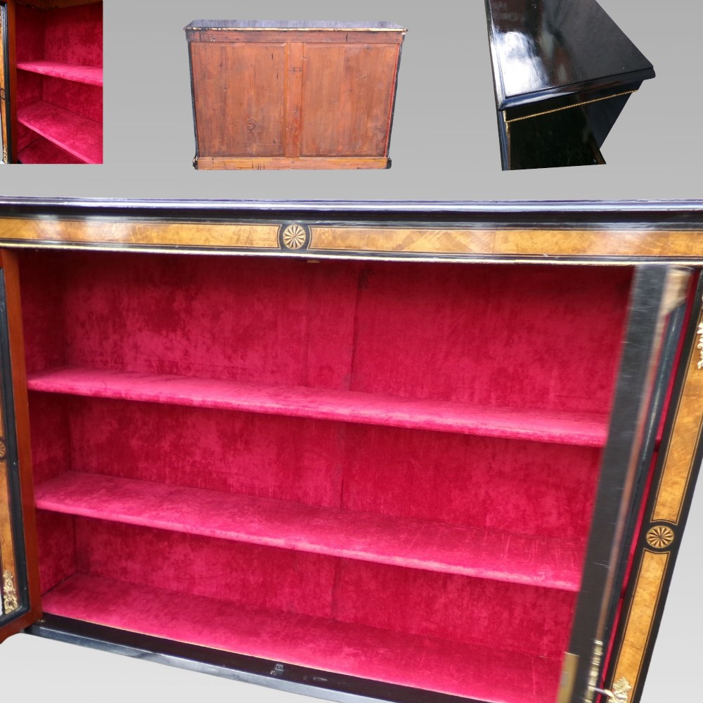 A 19th-century Victorian walnut and ebonised display cabinet featuring two glazed doors, gilt metal mounts, and a magenta velvet interior. View VI