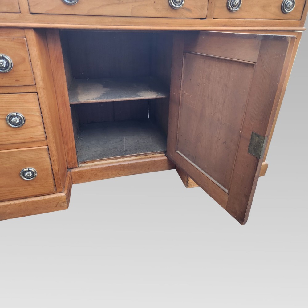 An antique Victorian pine pedestal writing desk featuring a green leather inset top and twin pedestals fitted with drawers and brass ring handles. View V