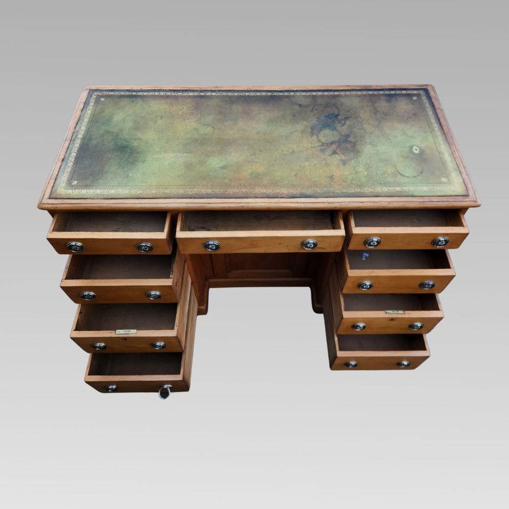An antique Victorian pine pedestal writing desk featuring a green leather inset top and twin pedestals fitted with drawers and brass ring handles. View VI