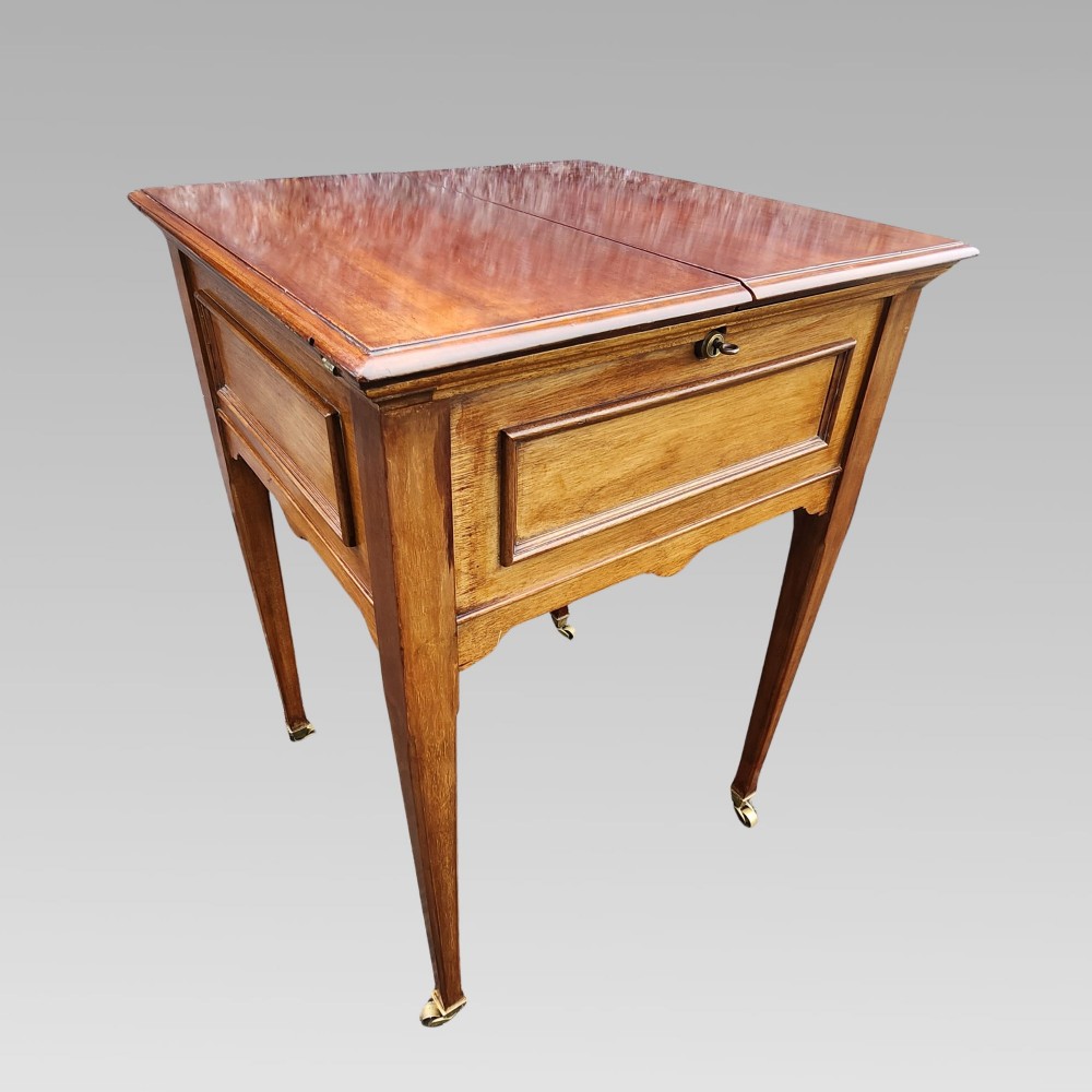 An open antique Edwardian mahogany metamorphic writing desk featuring fold-out side flaps, a green leather writing surface, integrated inkwells, and brass fittings. View II