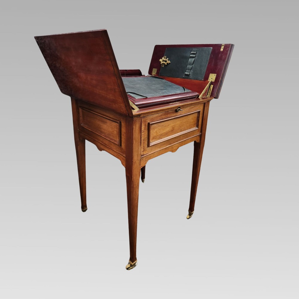 An open antique Edwardian mahogany metamorphic writing desk featuring fold-out side flaps, a green leather writing surface, integrated inkwells, and brass fittings. View III