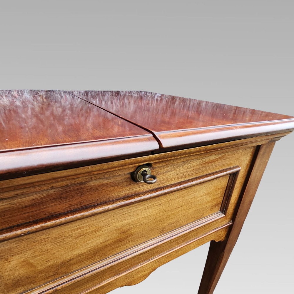 An open antique Edwardian mahogany metamorphic writing desk featuring fold-out side flaps, a green leather writing surface, integrated inkwells, and brass fittings. View IV