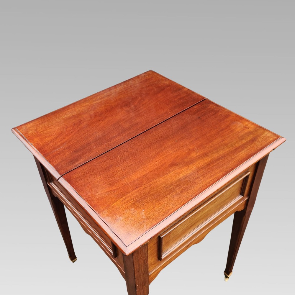 An open antique Edwardian mahogany metamorphic writing desk featuring fold-out side flaps, a green leather writing surface, integrated inkwells, and brass fittings. View V