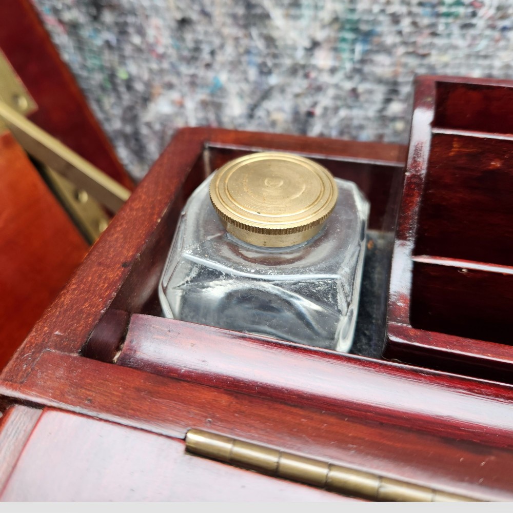 An open antique Edwardian mahogany metamorphic writing desk featuring fold-out side flaps, a green leather writing surface, integrated inkwells, and brass fittings. View VI