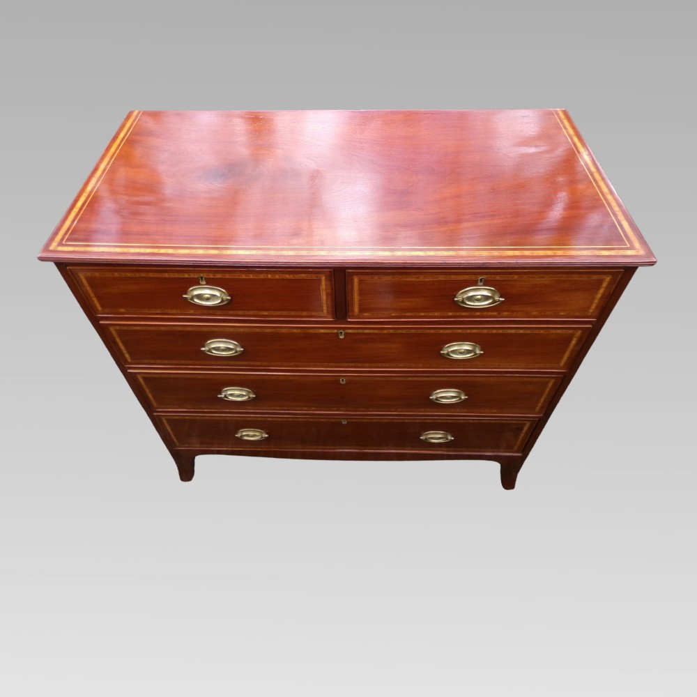A Victorian mahogany chest of drawers featuring two short over three long drawers with satinwood crossbanding and oval brass handles. View II