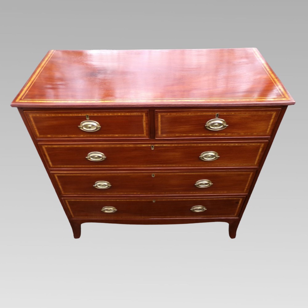 A Victorian mahogany chest of drawers featuring two short over three long drawers with satinwood crossbanding and oval brass handles. View IV