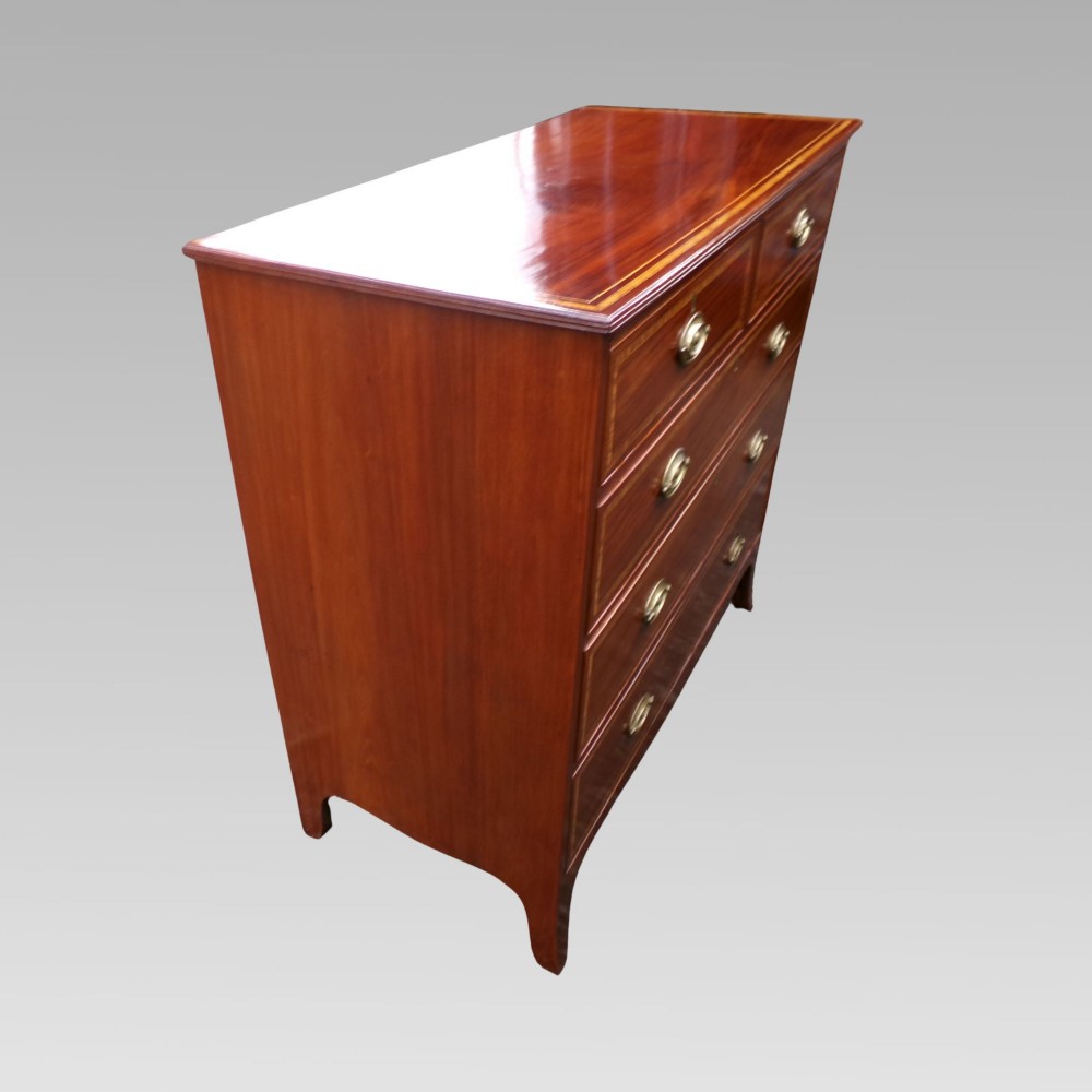 A Victorian mahogany chest of drawers featuring two short over three long drawers with satinwood crossbanding and oval brass handles. View VI
