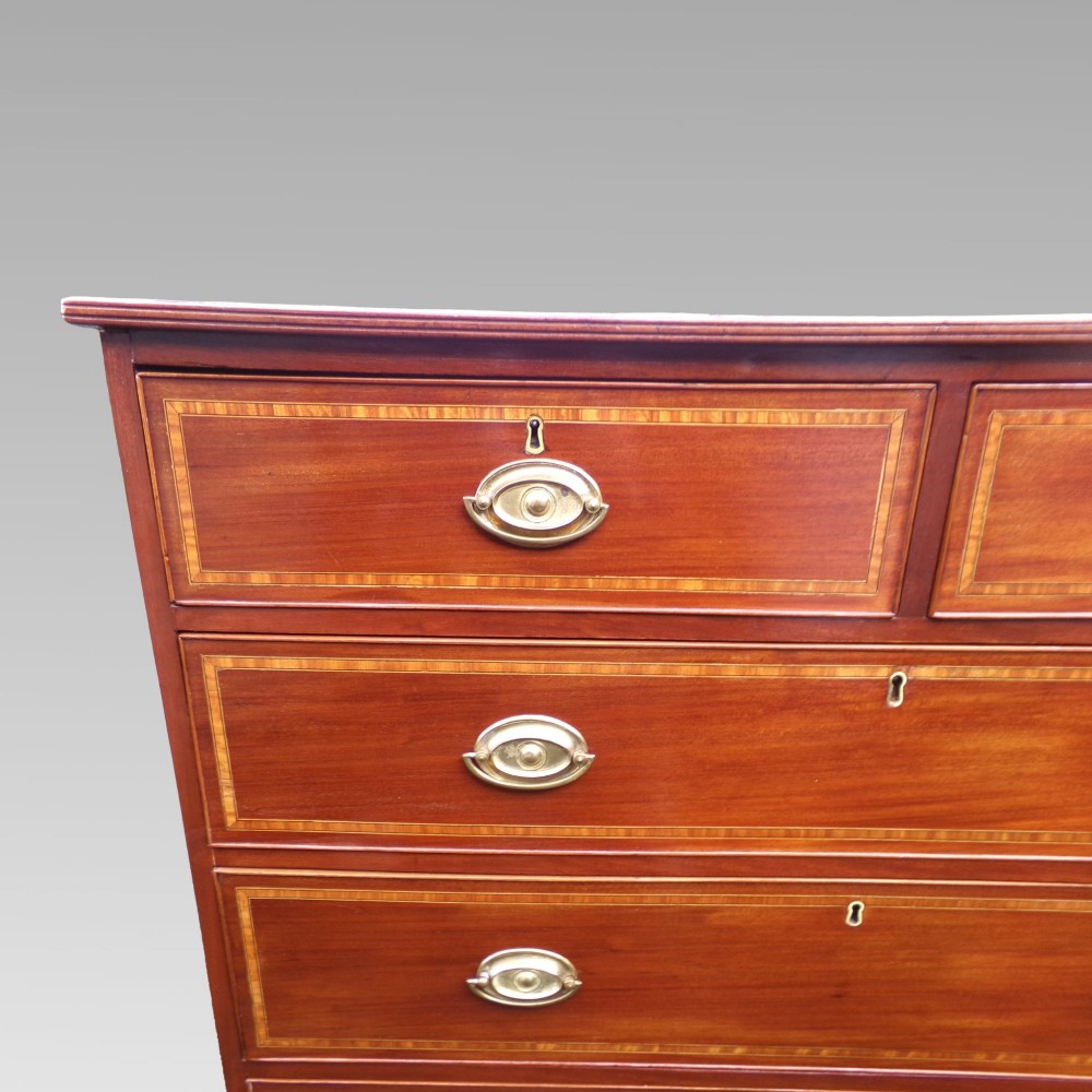 A Victorian mahogany chest of drawers featuring two short over three long drawers with satinwood crossbanding and oval brass handles. View VII