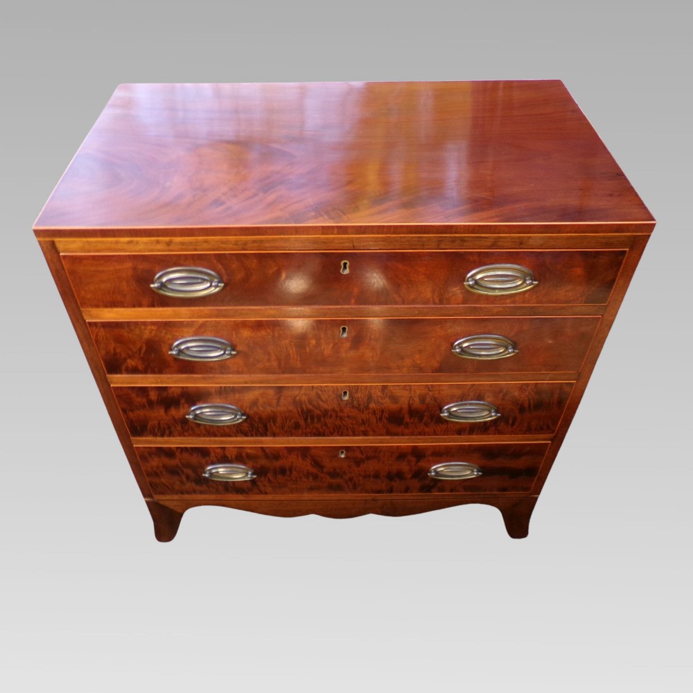 A George III style mahogany chest of four drawers featuring flame mahogany drawer fronts, satinwood line inlay, brass oval handles, and bracket feet.