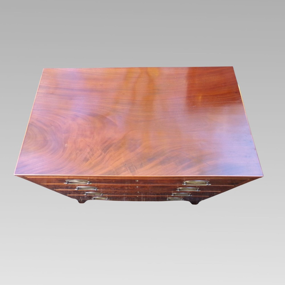 A George III style mahogany chest of four drawers featuring flame mahogany drawer fronts, satinwood line inlay, brass oval handles, and bracket feet. View III