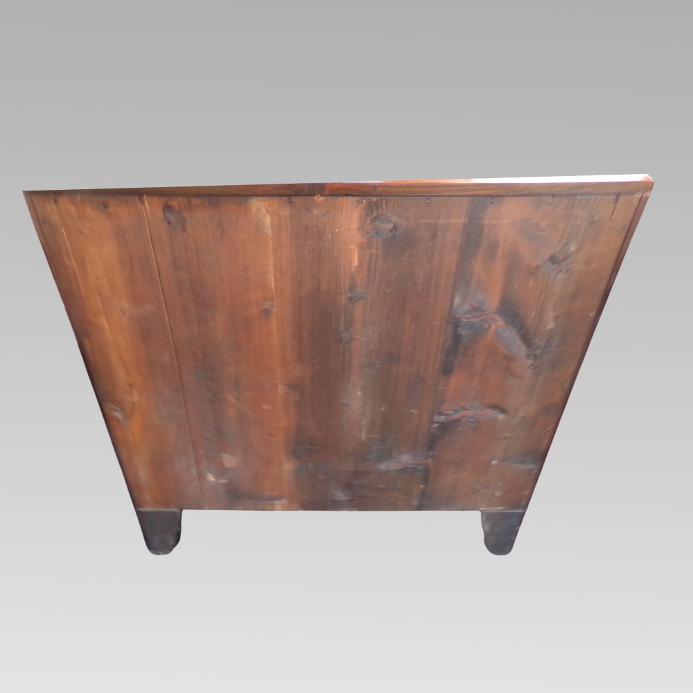 A George III style mahogany chest of four drawers featuring flame mahogany drawer fronts, satinwood line inlay, brass oval handles, and bracket feet. View V