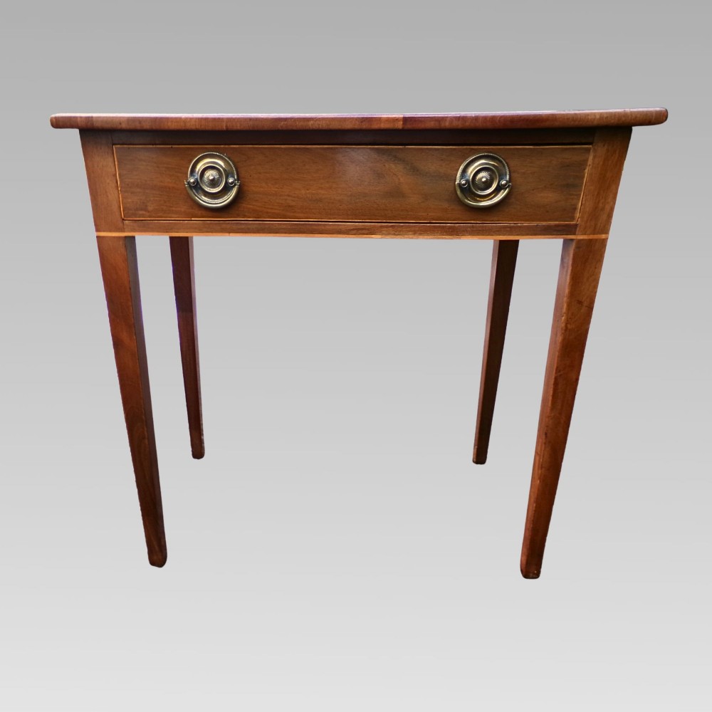 A George III mahogany side table with fine string inlay around the single drawer front and brass ring handles, raised on square tapered legs. View IV