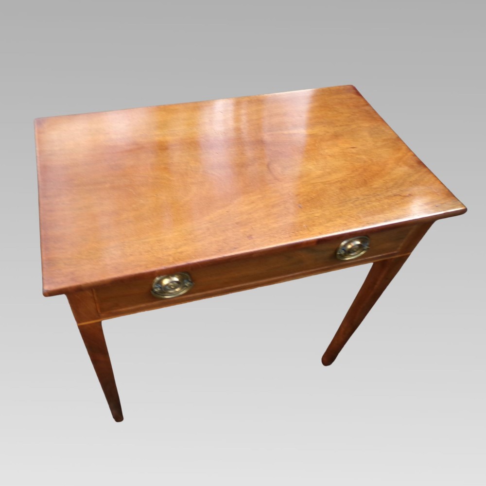 A George III mahogany side table with fine string inlay around the single drawer front and brass ring handles, raised on square tapered legs. View V