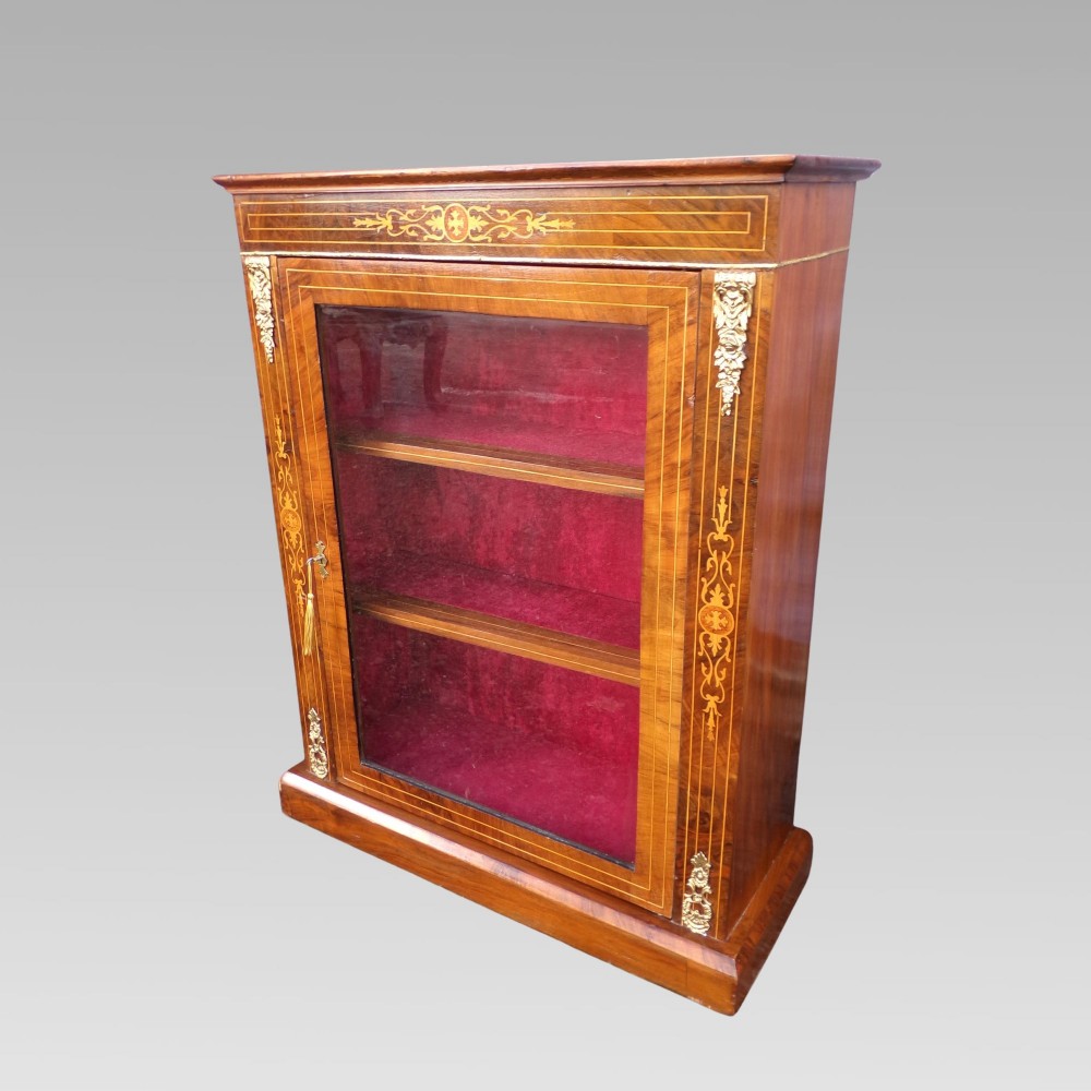 A nineteenth-century walnut veneer pier cabinet featuring floral marquetry inlay, gilt brass mounts, a single glazed door, and a red velvet lined interior. View II