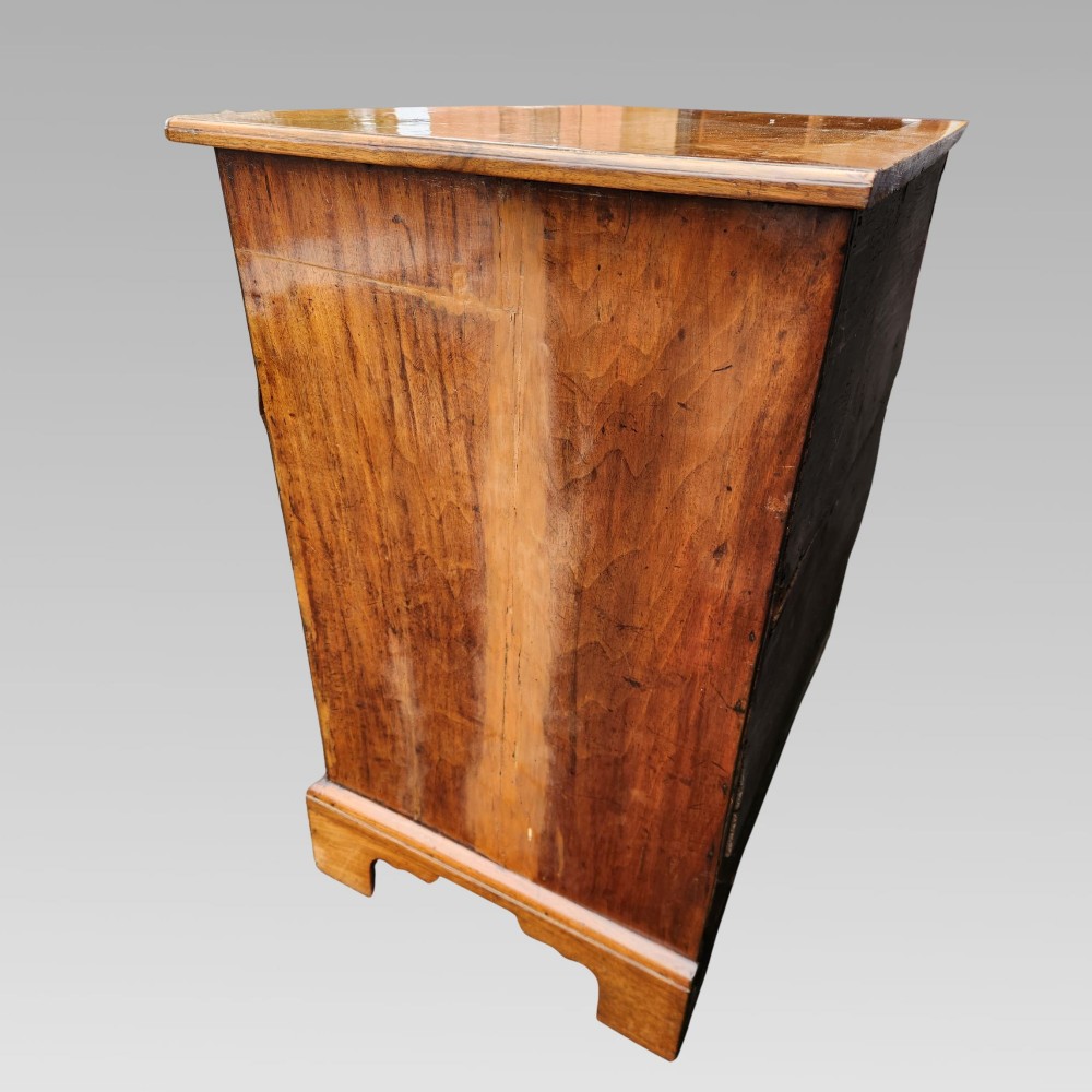 An antique Queen Anne style burr walnut kneehole desk featuring a crossbanded top, brass drop handles, a central recessed cupboard, and bracket feet. View IV