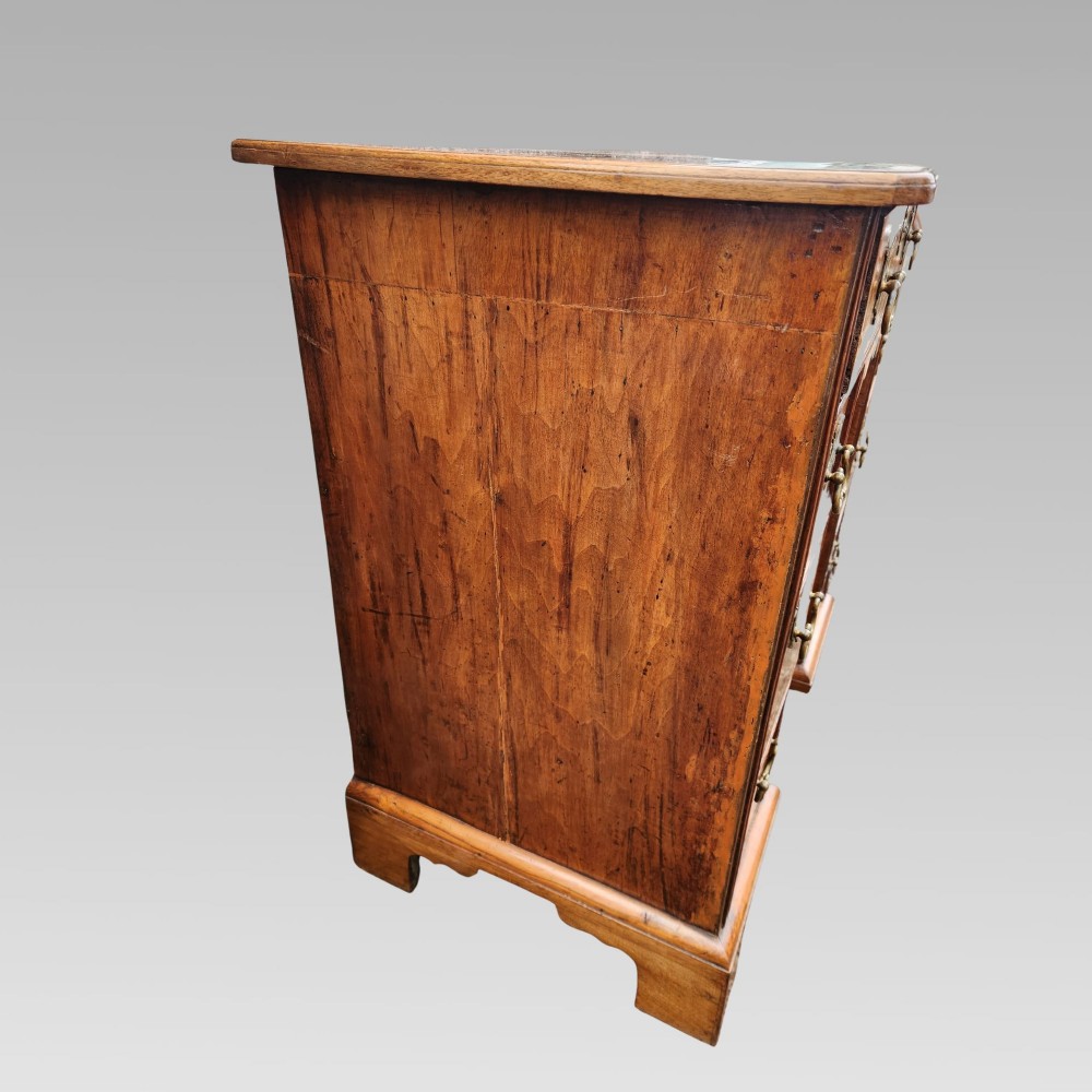 An antique Queen Anne style burr walnut kneehole desk featuring a crossbanded top, brass drop handles, a central recessed cupboard, and bracket feet. View V