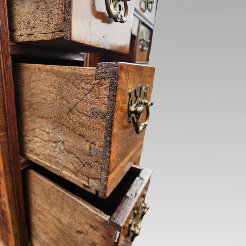 An antique Queen Anne style burr walnut kneehole desk featuring a crossbanded top, brass drop handles, a central recessed cupboard, and bracket feet. View VII