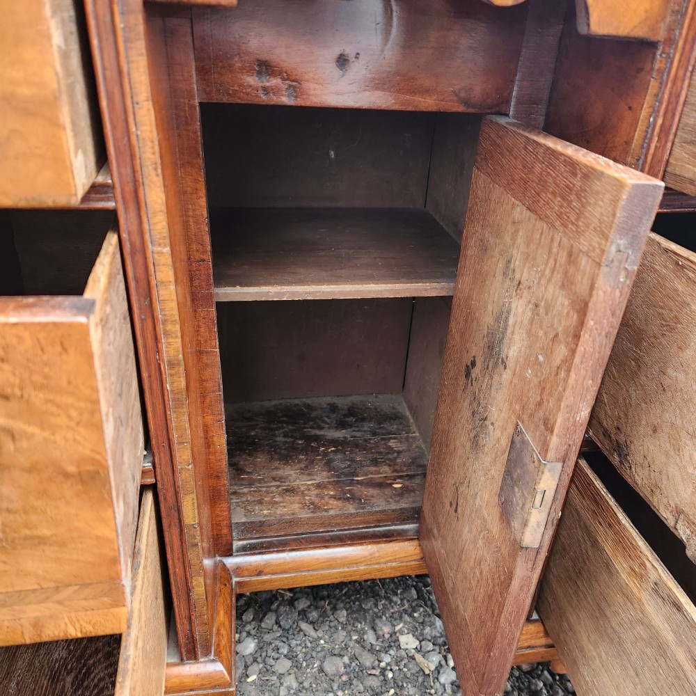 An antique Queen Anne style burr walnut kneehole desk featuring a crossbanded top, brass drop handles, a central recessed cupboard, and bracket feet. View VIII