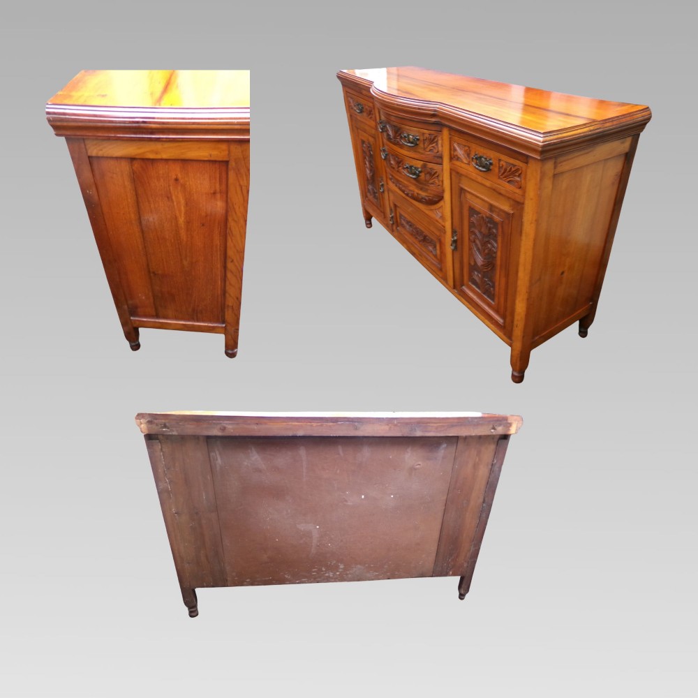 A carved Edwardian mahogany sideboard featuring a bow-front centre section with drawers, flanked by cupboard doors with stylised plant motifs. View V