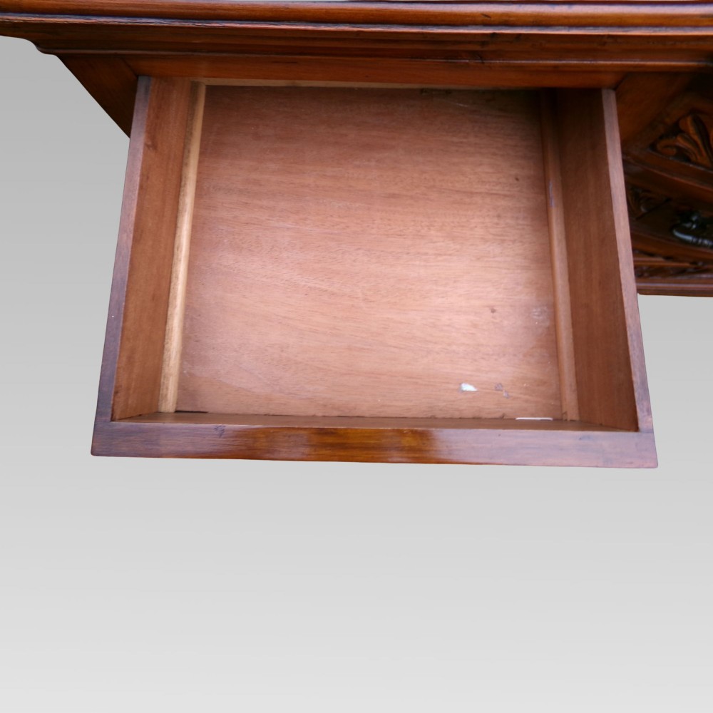 A carved Edwardian mahogany sideboard featuring a bow-front centre section with drawers, flanked by cupboard doors with stylised plant motifs. View X