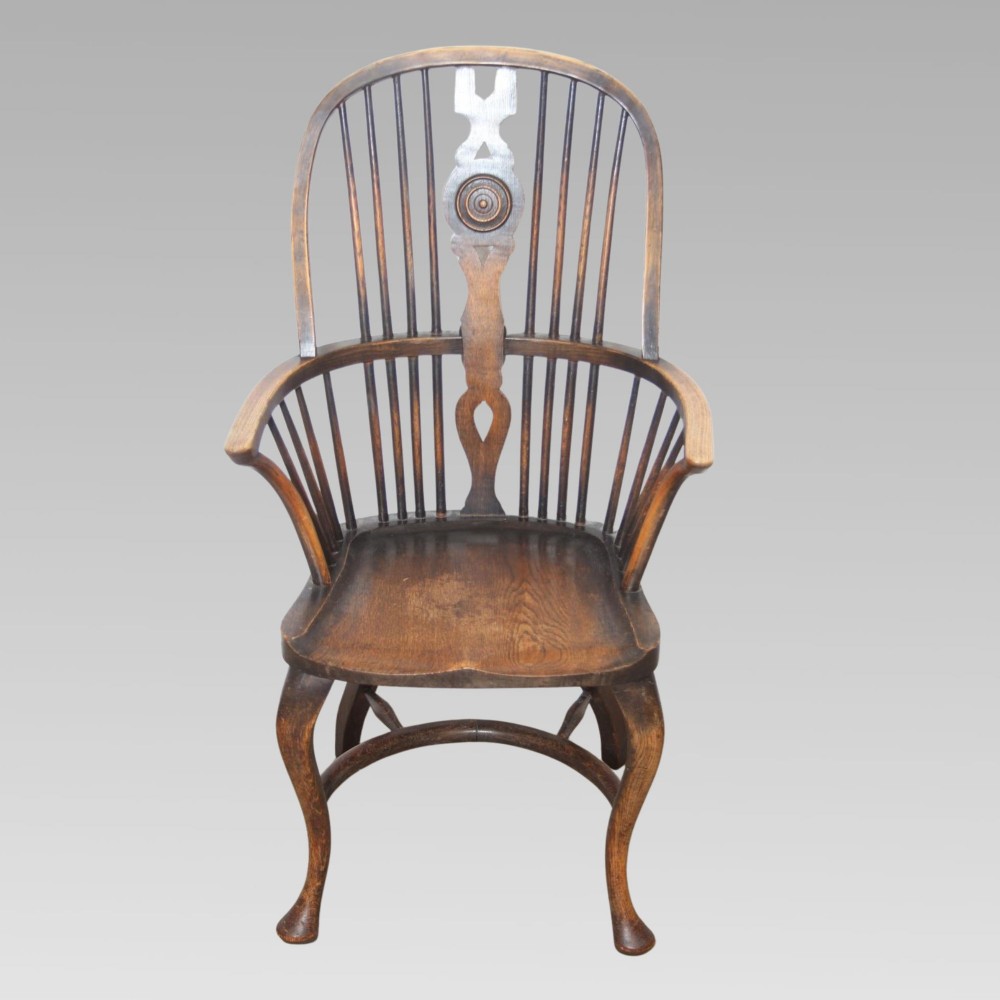 An antique dark oak Windsor armchair featuring a high bowed spindle back, a central carved bullseye splat, cabriole front legs, and a saddled wooden seat. View II