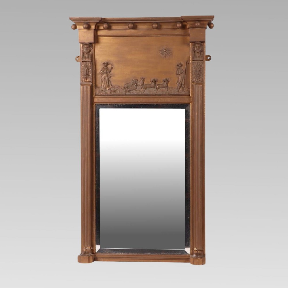A 19th-century giltwood pier mirror featuring Egyptian Revival pharaoh head pilasters, a moulded ball cornice, and a relief frieze panel above the rectangular glass.