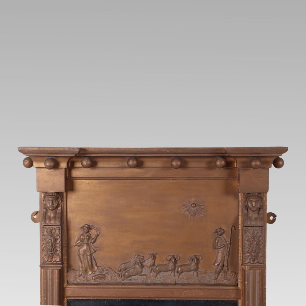 A 19th-century giltwood pier mirror featuring Egyptian Revival pharaoh head pilasters, a moulded ball cornice, and a relief frieze panel above the rectangular glass. View II