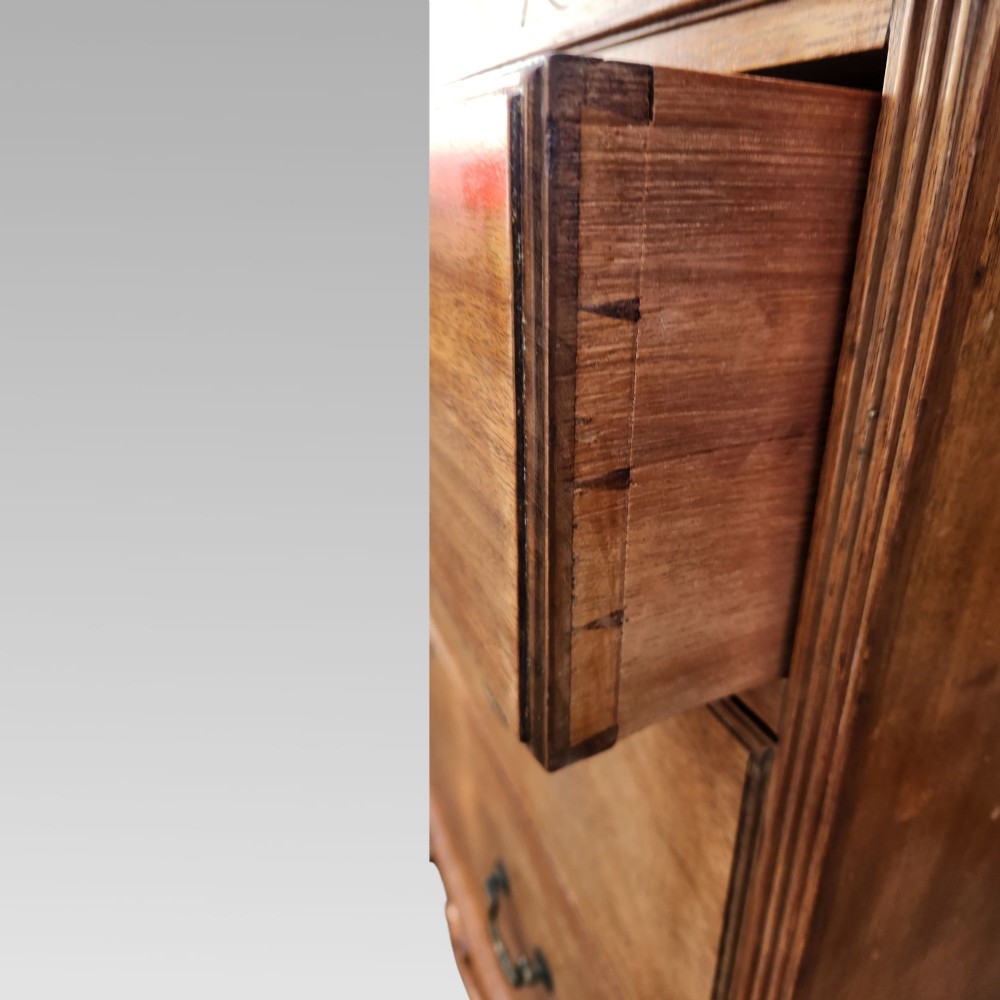 A Victorian mahogany chest of drawers featuring three horizontal drawers with brass handles, a carved wave frieze, and a shaped apron base. View IV