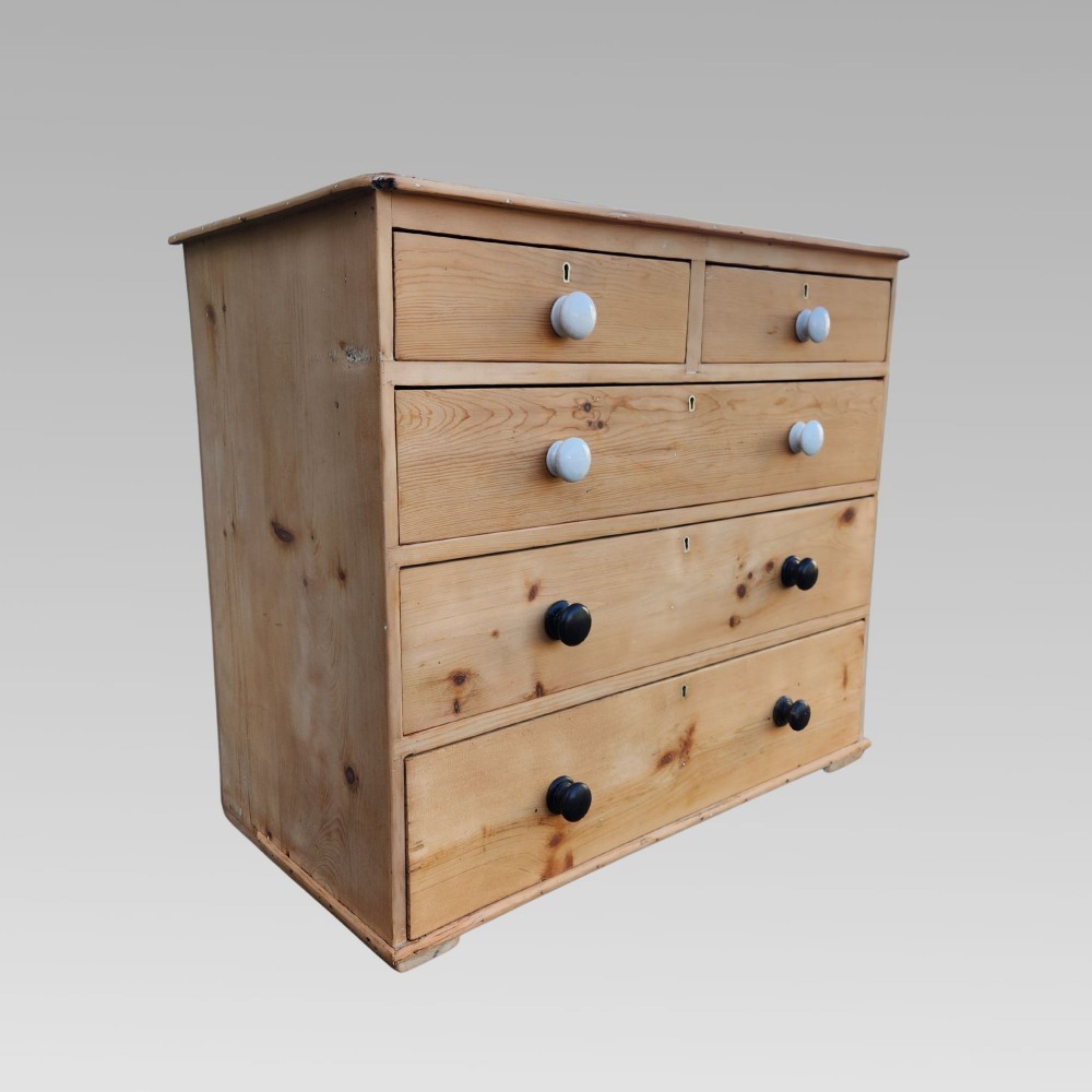 A 19th-century Victorian pine chest of drawers featuring two short over three long drawers with turned white ceramic and black wooden knobs. View V