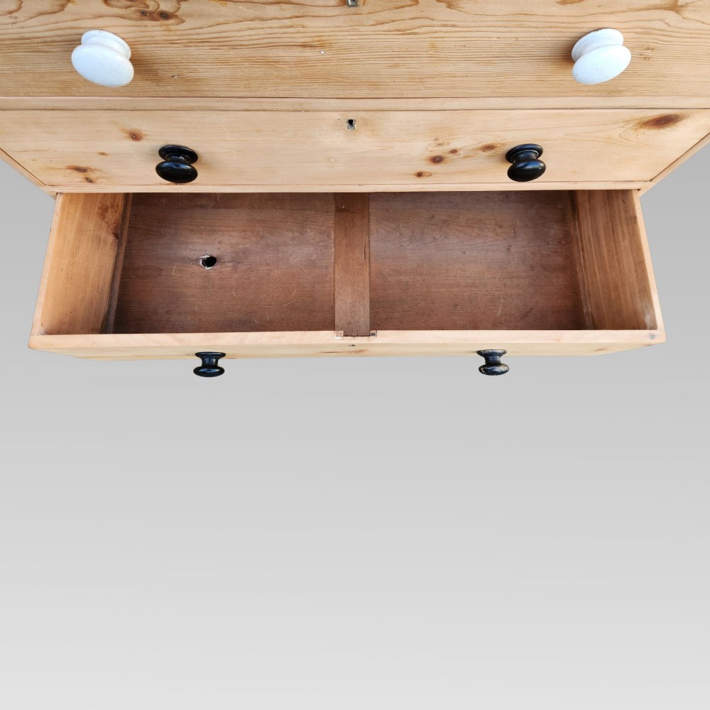 A 19th-century Victorian pine chest of drawers featuring two short over three long drawers with turned white ceramic and black wooden knobs. View IX
