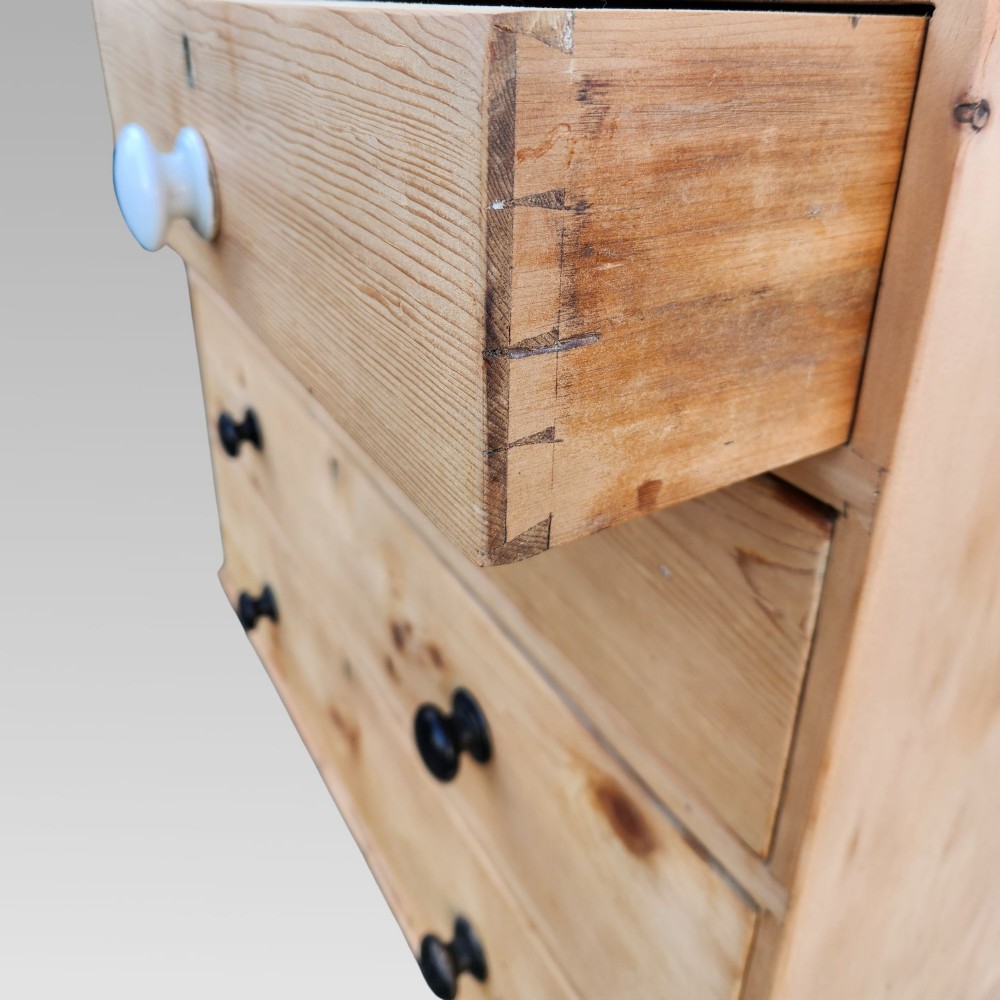 A 19th-century Victorian pine chest of drawers featuring two short over three long drawers with turned white ceramic and black wooden knobs. View X