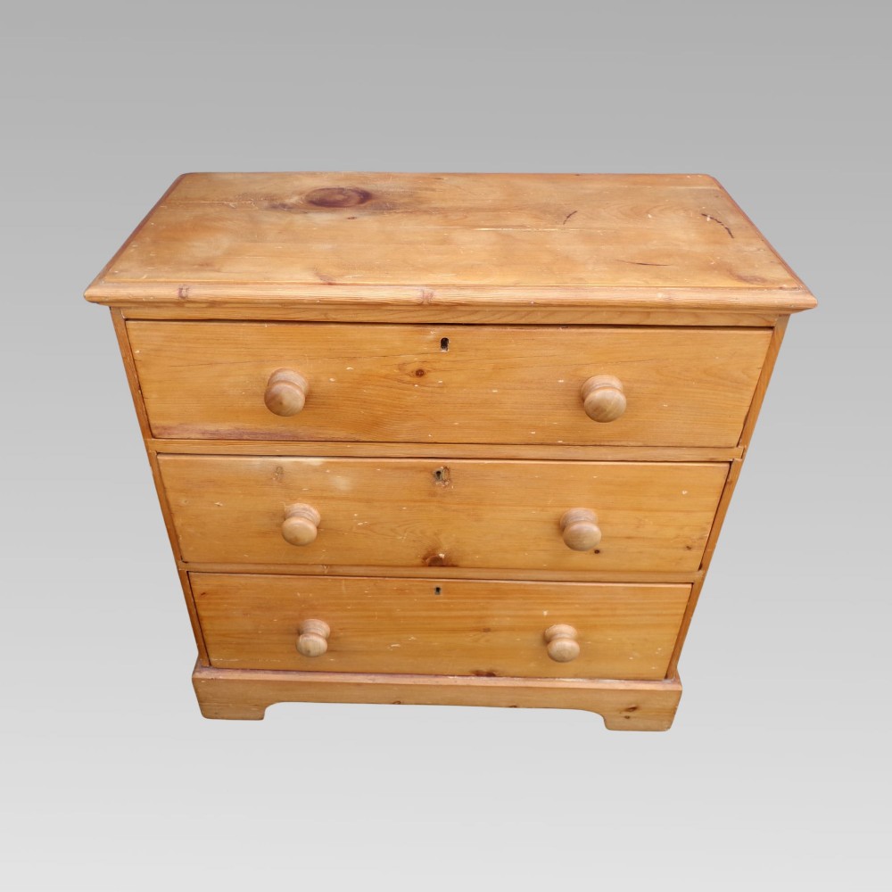 A nineteenth-century Victorian pine chest featuring three full-width drawers with turned wooden handles and keyholes, set on a plinth base. View II