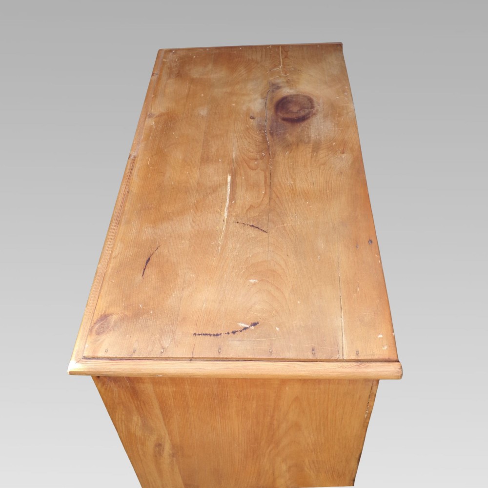 A nineteenth-century Victorian pine chest featuring three full-width drawers with turned wooden handles and keyholes, set on a plinth base. View IV