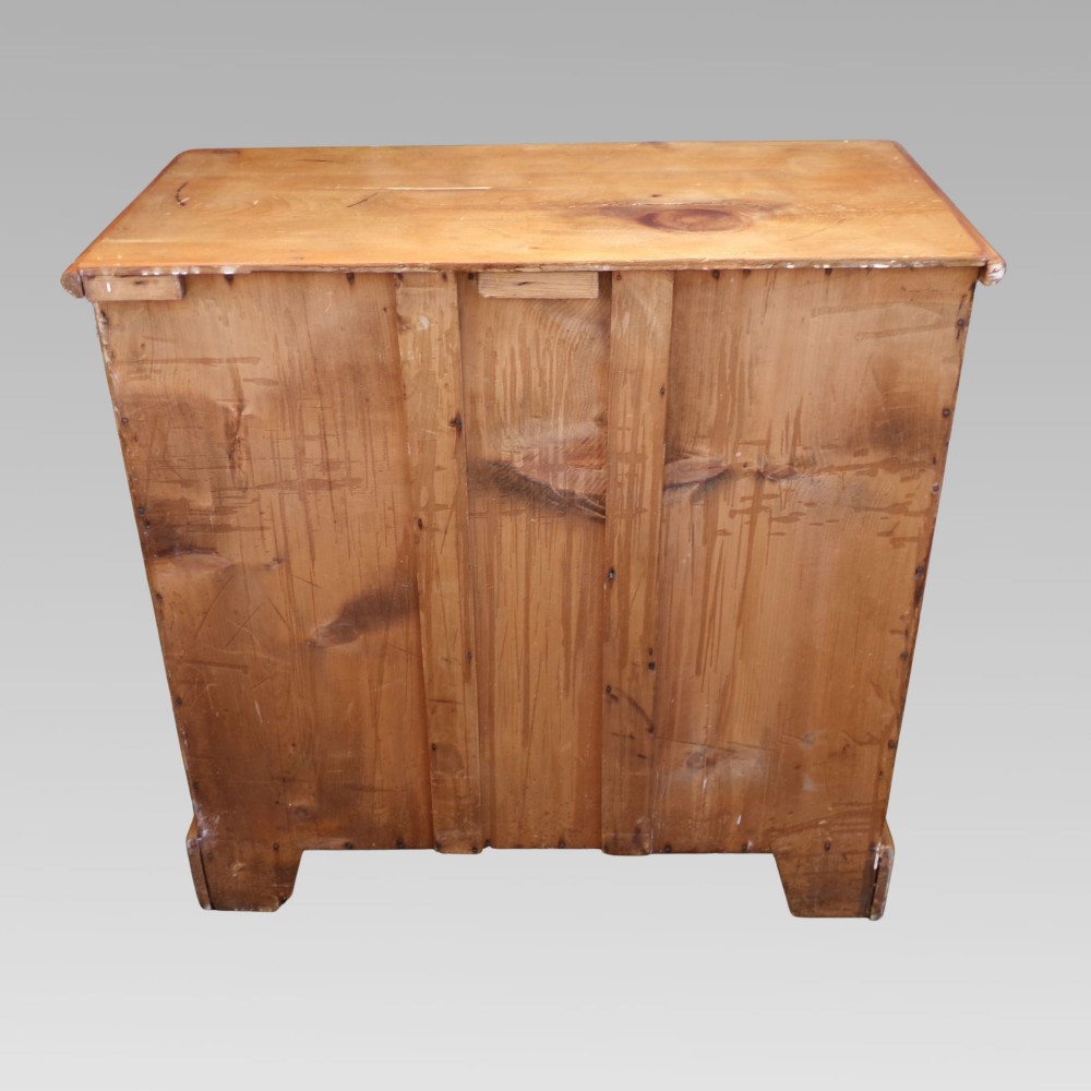 A nineteenth-century Victorian pine chest featuring three full-width drawers with turned wooden handles and keyholes, set on a plinth base. View V